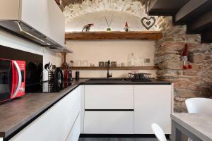 a kitchen with white cabinets and a stone wall at Chez Margot Et Sophie in Torgnon