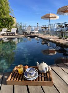 a table with a tea set next to a swimming pool at Maison D'hôtes Casa Ghjunca in Rapale