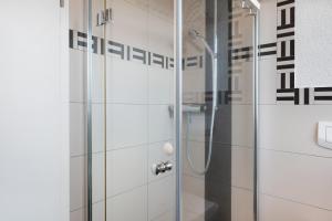 a shower in a bathroom with white tiles at Ferienwohnungen Steiert in Freiburg im Breisgau +30 photos