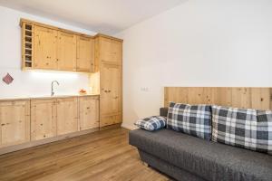 a living room with a couch and a kitchen at Ciasa Silvia in San Martino in Badia +12 photos