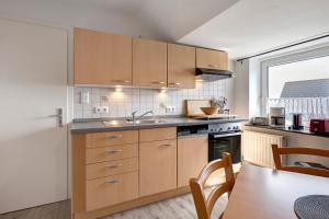a kitchen with wooden cabinets and a sink and a table at Gästehaus Tadenswarf in Tadenswarf