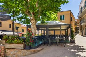 a restaurant with tables and chairs under a tree at Appartamenti Remota in Castiglione della Pescaia