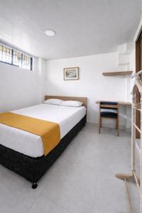 ein Schlafzimmer mit einem Bett, einem Schreibtisch und einem Tisch in der Unterkunft Hotel Adel in Manizales