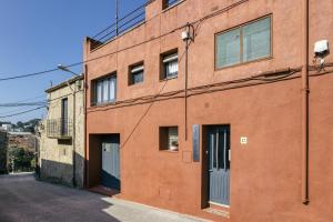 an orange brick building with two doors on a street at Can Picola in Capmany