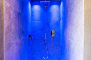 a blue tiled bathroom with a shower with a hose at Hoamat Schlosshof in Völs am Schlern +31 photos