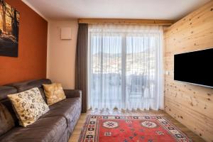a living room with a couch and a large window at Ciasa Rungg App Corones in San Vigilio Di Marebbe