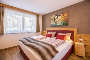a bedroom with a large bed with a tree painting on the wall at Ciasa Rungg App Corones in San Vigilio Di Marebbe