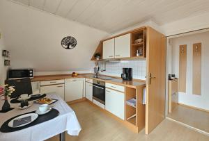 a small kitchen with white cabinets and a table at Haus Rosenfelder Fewo Abendsonne in Bernau im Schwarzwald