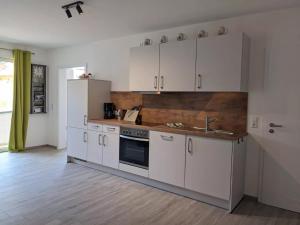 a kitchen with white cabinets and a sink at Fewo New Oberdorf in Fautenbach