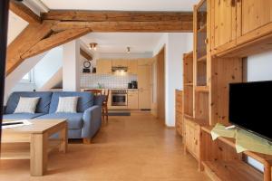 a living room with a blue couch and a kitchen at Haus Hilebrand in Kressbronn am Bodensee