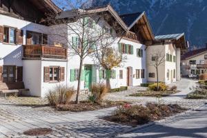 a large white building with green shutters on a street at Ferienwohnung Rosenquarz in Mittenwald