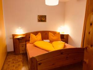 a bedroom with a wooden bed with yellow pillows at Residence Zirmer Wohnung Sonne in Castelrotto