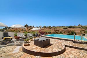 a pool with umbrellas and a patio at Casa dos Jotas in Martinlongo