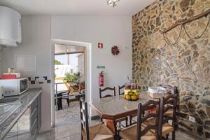 a kitchen and dining room with a stone wall at Casa dos Jotas in Martinlongo