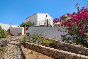 a house with flowers and a stone wall at Casa dos Jotas in Martinlongo