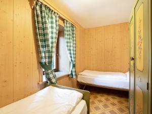 a small room with two beds and a window at Ciasa Lino Sas da le Doudesc in Pozza di Fassa