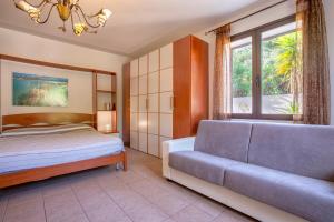 a bedroom with a bed and a couch and a window at Villa Patrizia in Castelsardo +35 photos