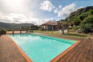 a swimming pool with a wooden deck and a house at Villa Patrizia in Castelsardo