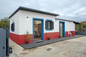 a small white house with blue and red accents at Litlle Zen House in Santana