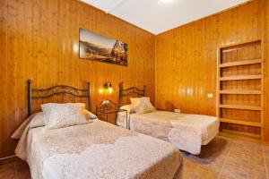 two beds in a room with wooden walls at Casa Doña Margarita in Tuineje