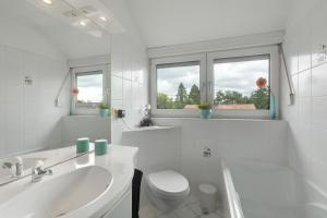 a white bathroom with a toilet and a sink at Ferienwohnung Ruhepol, 75qm in Vellmar +16 photos