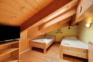 a room with two beds and a flat screen tv at Casa Aliza - Duplex Alpino in Pieve di Bono