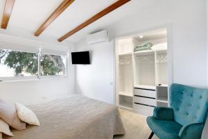 a white bedroom with a bed and a blue chair at El chiringuito in Candelaria