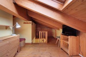 an attic room with wooden beams and a tv at Casa Aliza - Duplex Alpino in Pieve di Bono