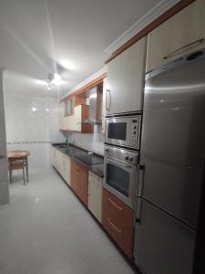 a kitchen with wooden cabinets and stainless steel appliances at O Son in Cee