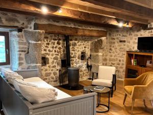 a living room with stone walls and a bed and chairs at Le Chant du Grillon in Le Nayrac