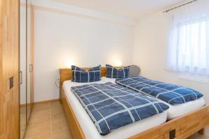 a bedroom with a bed with blue comforter and pillows at Ferienwohnung Lauser Ug in Herdwangen-Schönach
