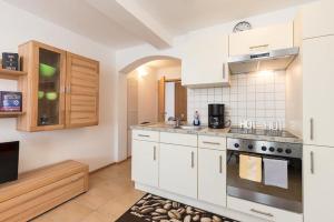 a kitchen with white cabinets and a stove at Ferienwohnung Lauser Ug in Herdwangen-Schönach +4 photos