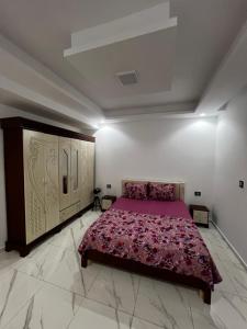 a bedroom with a purple bed in a white room at Villa charme in Awlād ‘Umar