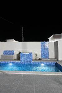 a swimming pool at night with blue tiles at Villa charme in Awlād ‘Umar +4 photos