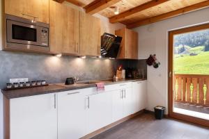 a kitchen with white cabinets and a microwave at Schererhof Morgenrot in Castelrotto