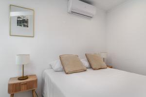 a white bedroom with a bed with two lamps at Birre House in Cascais