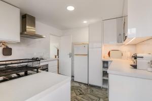 a kitchen with white cabinets and a refrigerator at Birre House in Cascais