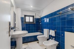 a blue tiled bathroom with a toilet and a sink at Birre House in Cascais +20 photos