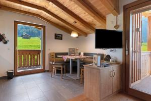 a living room with a television and a table with chairs at Schererhof Morgenrot in Castelrotto