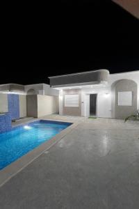 a swimming pool in a building at night at Villa charme in Awlād ‘Umar