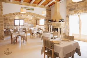 a restaurant with white tables and chairs and stone walls at Masseria Scafazzi - Salento in Presicce