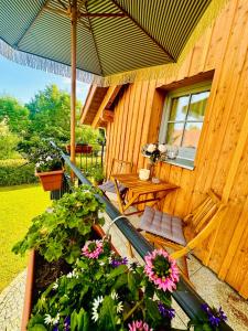 a wooden house with an umbrella and a table and flowers at Aubrac-Biohof Königshainer Berge in Königshain +7 photos