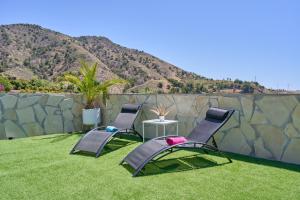 two chairs and a table on a lawn with a mountain at Casa Rural El Granado in Nerja