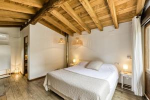 a bedroom with a white bed and wooden ceilings at El Niu in Montagut