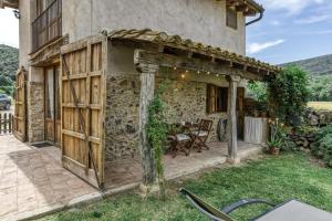 an outdoor patio with a stone building with a wooden pergola at El Niu in Montagut