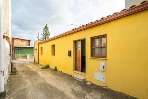 a yellow building with a door on a street at Agata House in Muravera