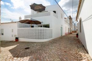a white building with an umbrella on a street at Casa de Benafim 51 in Benafim