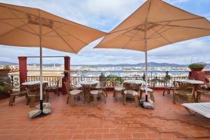 a patio with tables and chairs and umbrellas at Navila Estudio en la piscina in Ibiza Town
