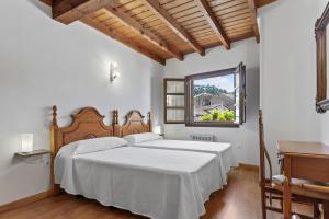 a bedroom with a large white bed and a window at Apartamentos El Rincón de Bustio in Bustio