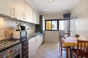 a kitchen with a table and a stove top oven at Quarteira Beach I in Quarteira